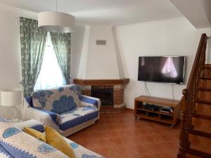 a living room with a couch and a tv at Casa de praia em Almograve in Almograve