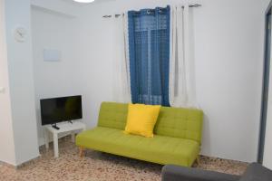 ein grünes Sofa im Wohnzimmer mit TV in der Unterkunft Gran Notch in Alicante