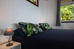 a bed with two pillows and a table with a lamp at Bienvenue au Mati House in Fitii