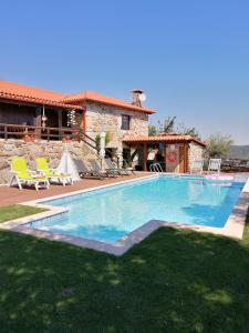 a large swimming pool with chairs and a house at Casa da Montanha in Rebordões