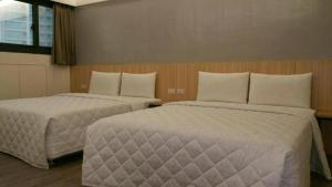 a hotel room with two beds with white pillows at 萬酈精品旅館 in Kaohsiung