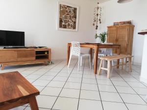 a living room with a table and chairs and a tv at ROCHES PERCEES *** in Terre-de-Haut