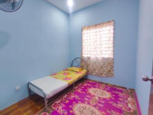 a small room with a bed and a window with a rug at Teratak Aqish, Besut Terengganu in Kampong Gong Pauh