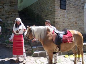 a man and a woman standing next to a horse at Staroto Shkolo House - rooms for guests in Sŭbotkovtsi