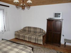 a living room with a couch and a tv on a cabinet at Staroto Shkolo House - rooms for guests in Sŭbotkovtsi