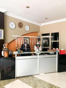 a kitchen with clocks on the wall and a counter at Central City Hotel in Perabumulih