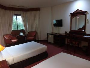 a hotel room with a bed and a desk and a mirror at Inn Come Hotel Chiang Rai in Chiang Rai