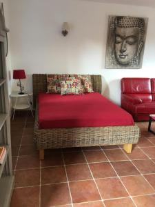 a bed in a room with a couch and a red blanket at Gite du Petit Tesseau in Candé