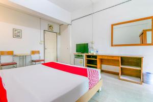 1 dormitorio con cama blanca y espejo en OYO 1161 Sathorn Mansion en Nakhon Ratchasima