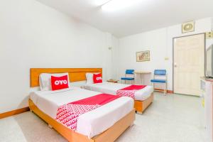 1 dormitorio con 2 camas, mesa y sillas en OYO 1161 Sathorn Mansion en Nakhon Ratchasima