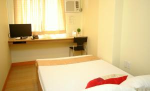 a room with two beds and a desk with a television at Anri Pension House in Cebu City
