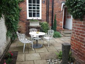 un patio con tavolo, sedie e un edificio di The Red House a Grantham