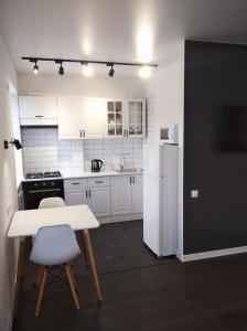 a white kitchen with a table and a white refrigerator at White Apartment in Poltava