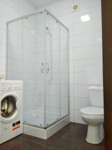 a bathroom with a shower and a toilet and a washing machine at White Apartment in Poltava