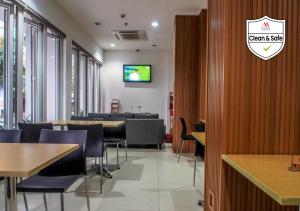a restaurant with tables and chairs and a tv on the wall at M Hotel Jakarta in Jakarta
