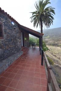 ein Steinhaus mit einer Terrasse und einer Palme in der Unterkunft Casas Rurales Los Manantiales in El Cercado