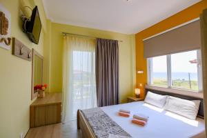 a bedroom with a bed and a large window at Dionisos Apartments in Paralia Dionysiou