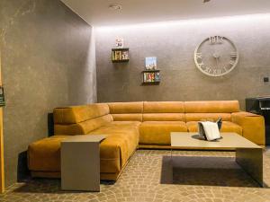 a living room with a brown couch and a clock at Penzión & Wellness MERIDIANA Bojnice rezort in Bojnice