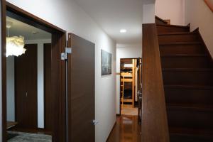 un couloir avec un escalier et une porte menant à une chambre dans l'établissement Auberge du Tanuki Noir Maison d'Hôtes, à Osaka