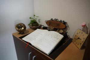 un livre ouvert assis sur un bureau avec une horloge dans l'établissement Auberge du Tanuki Noir Maison d'Hôtes, à Osaka