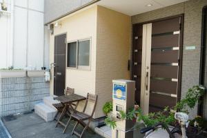 un patio con 2 sillas y una mesa en una casa en Auberge du Tanuki Noir Maison d'Hôtes, en Osaka