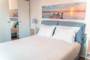 Un dormitorio con una cama blanca y una pintura en la pared en Sifanto Mare Apartments, en Faros