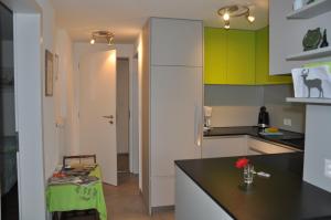 eine Küche mit grünen und weißen Schränken und einem Tisch in der Unterkunft La Ruche in Tramelan