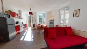 sala de estar con sofá rojo y cocina en Chez Gasti, en Colmar
