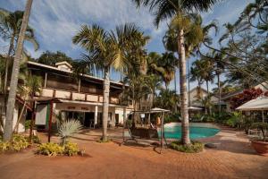 un complejo con piscina y palmeras en Tamboti Lodge Guest House en Tzaneen