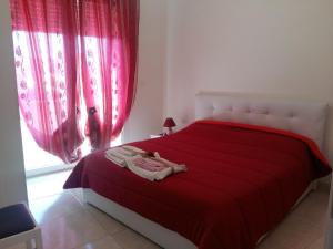 sypialnia z czerwonym łóżkiem z czerwoną pościelą i oknem w obiekcie Appartamento Pompea w mieście Taviano