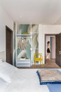 - une chambre avec un lit blanc et une chaise jaune dans l'établissement San Leonardo Suites, à Vérone