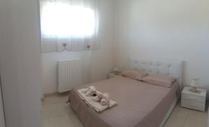 a white bedroom with a bed with a window at Appartamento Pompea in Taviano