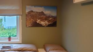 a bedroom with a picture of a mountain on the wall at På Hjørnet Gjestehus in Skjervøy