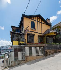 a yellow house with a white fence in front of it at Nắng Chiều Central Hotel in Da Lat