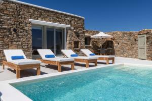 a villa with a swimming pool with chairs and an umbrella at Mykonos Divino in Tourlos