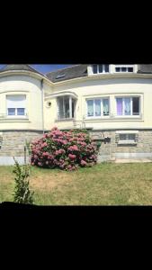 a large white house with a bush of pink flowers at Vos vacances dans le Morbihan in La Chapelle-Caro