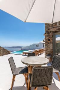 a patio with a table and chairs and a pool at Mykonos Divino in Tourlos