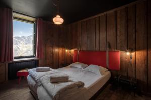 1 dormitorio con 1 cama con cabecero rojo y ventana en Refuge du Montenvers en Chamonix-Mont-Blanc