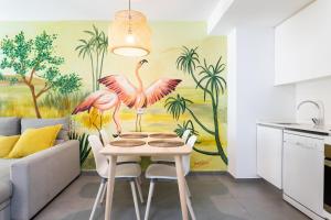 uma cozinha com uma mesa e um mural de flamingos cor-de-rosa em Apartamentos Las Terrazas de Sotavento em La Mareta