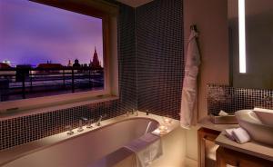ein Bad mit einer Badewanne, einem Waschbecken und einem Fenster in der Unterkunft The Grand Mark Prague - The Leading Hotels of the World in Prag