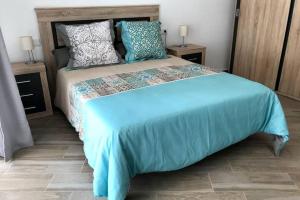 1 dormitorio con 1 cama grande con sábanas y almohadas azules en Espacioso y céntrico piso con zona chill-out, en Alicante