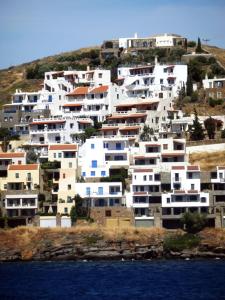 a group of white buildings on a hill with water at Meltemi in Vourkari