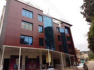 a building on a street with a car parked in front at Vinayaga Inn by Poppys, Ooty in Ooty