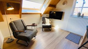 ein Wohnzimmer mit einem Stuhl und einem TV in der Unterkunft Studio Burg.bosselaarstraat in Aagtekerke