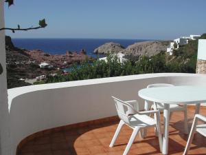 balcón con mesa, sillas y vistas al océano en Apartamentos Sa Cornisa, en Cala Morell