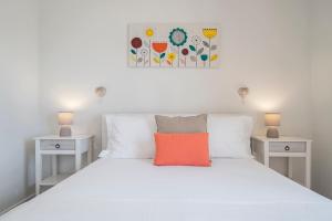 uma cama branca com uma almofada laranja em cima em Terrace Vila by An Island Apart no Caniço
