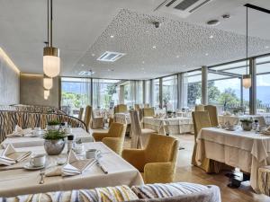 un restaurant avec des tables blanches, des chaises et des fenêtres dans l'établissement Hotel Traubenheim, à Tirolo