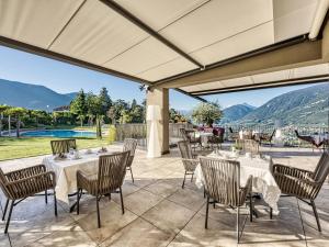 a patio with tables and chairs and a view of the mountains at Hotel Traubenheim in Tirolo