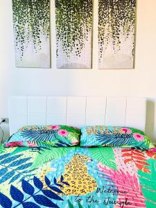 1 cama con un edredón colorido y 4 pinturas en la pared en Maiden-Art Apartment, en Arona