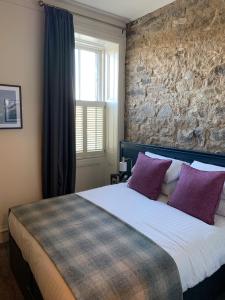 1 dormitorio con 1 cama grande con almohadas moradas en The Balerno Inn en Edimburgo